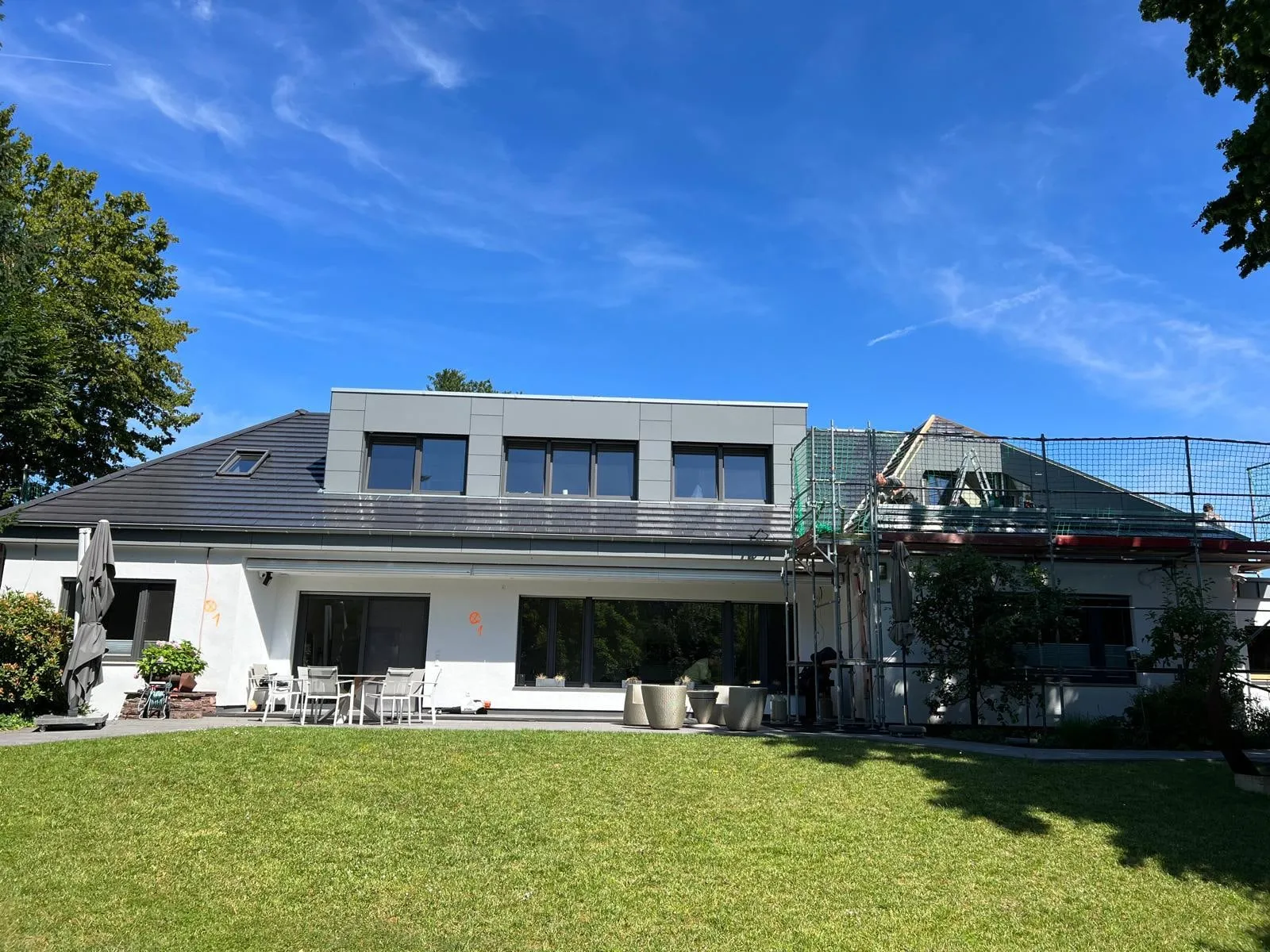 Gartenansicht mit dem fertigen Dach, rechts noch das Gerüst
